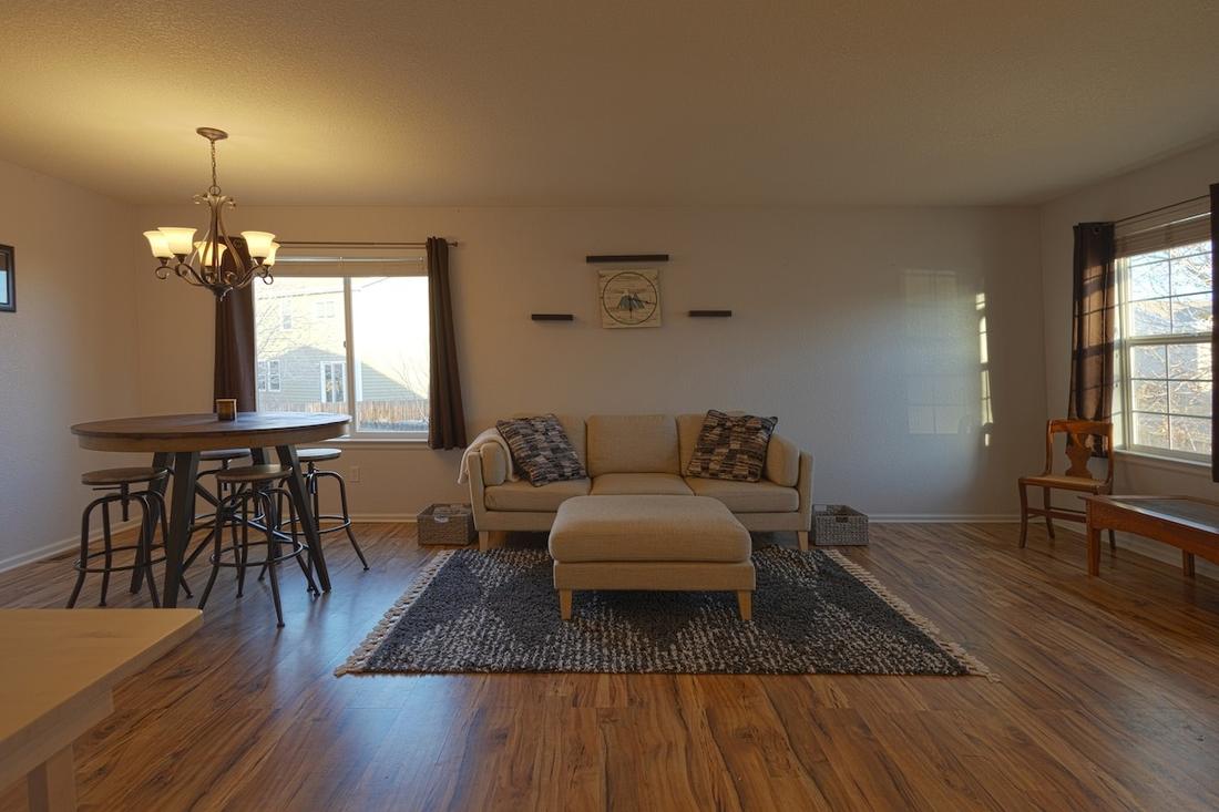 Bright living room with sofa, ottoman, and large windows