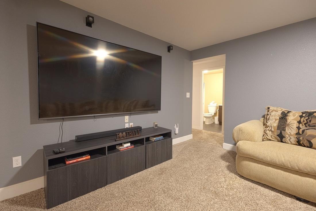 Lower-level media room with a large wall-mounted screen